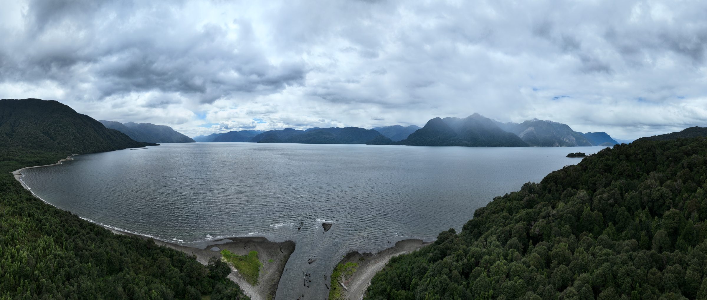 A fjord in the Aysén region from a drone - steep forested slopes dropping straight into the water